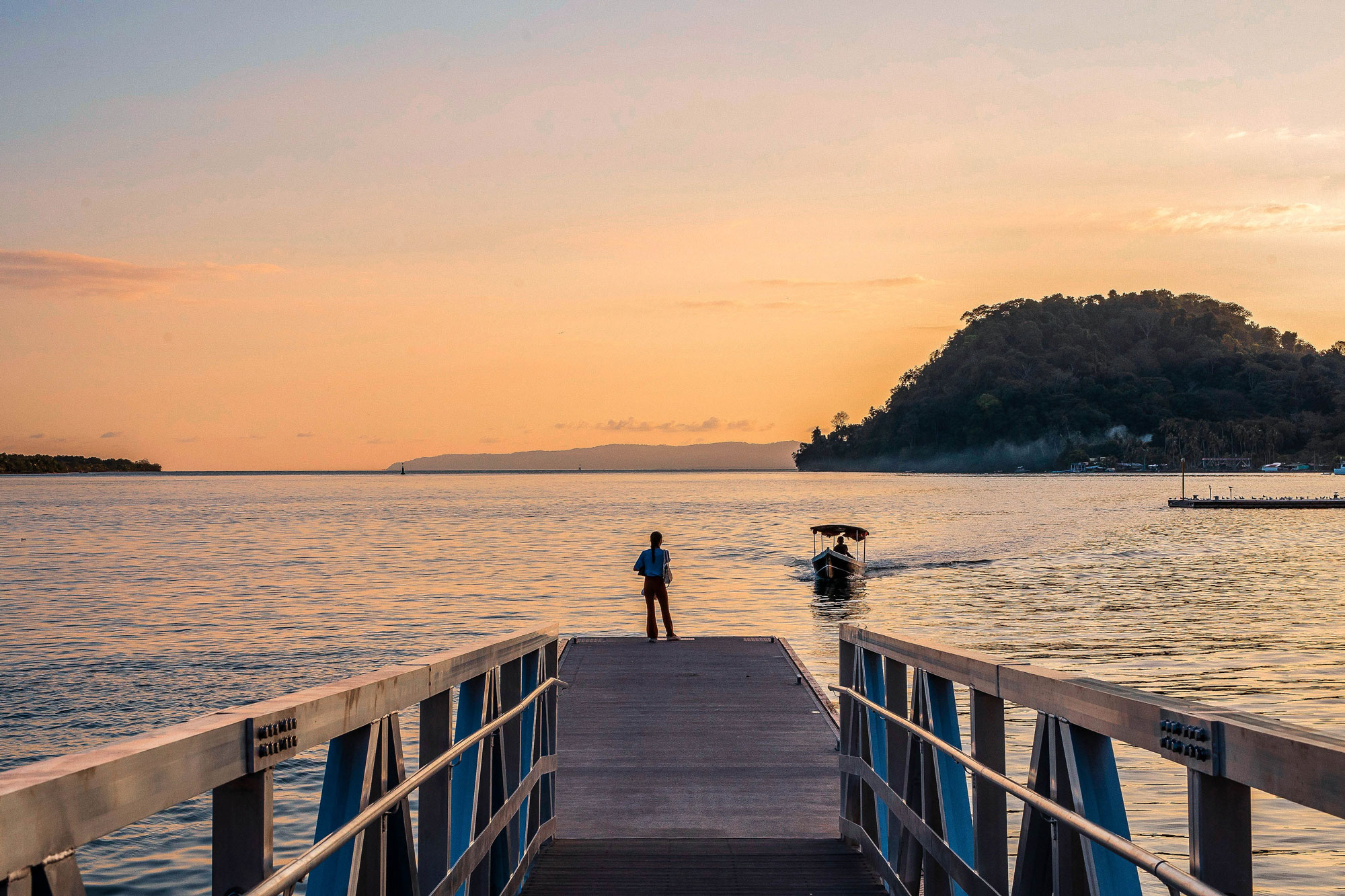 Person on dock at sunset watching a boat return to Marina Bahía Golfito