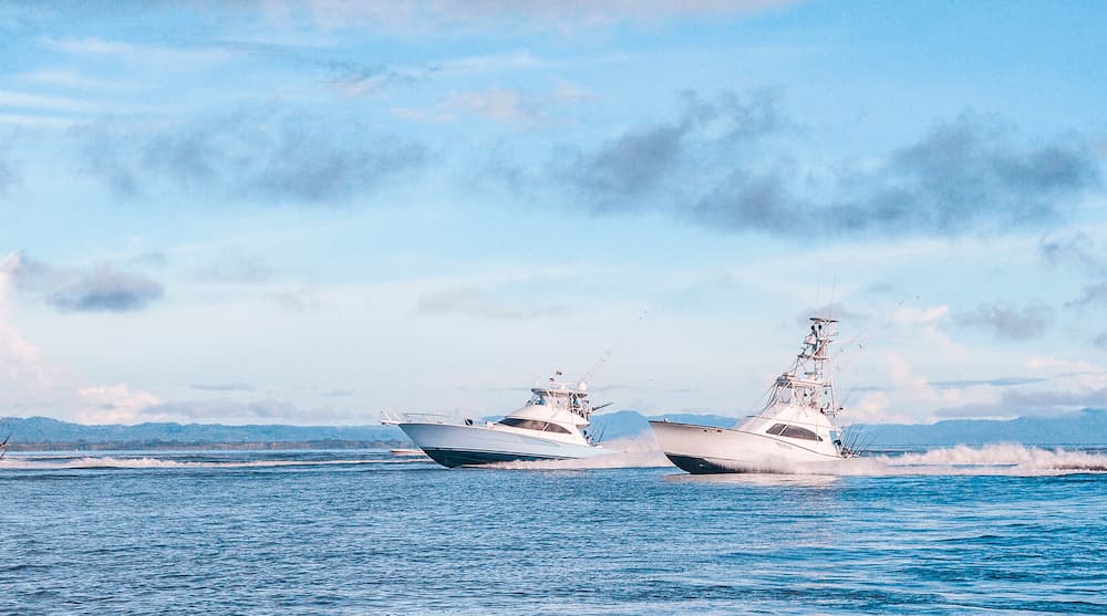 Two sportfishing yachts running across the Golfo Dulce with rainforest mountains behind them near Golfito, Costa Rica.