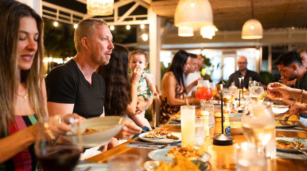 Families and friends sharing an evening meal at a waterfront restaurant in the Marina Village at Marina Bahia Golfito, Costa Rica.