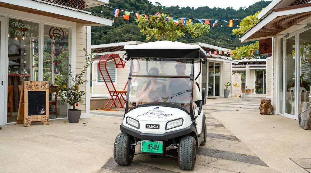 Visitors touring the Marina Village boutique shops and specialty coffee cafe at Marina Bahia Golfito by golf cart